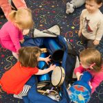 Toddlers reaching into the instrument bag, getting ready for the jam session in music class for 1-2 year olds