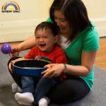 Mom and baby play the tambourine and maracas together.